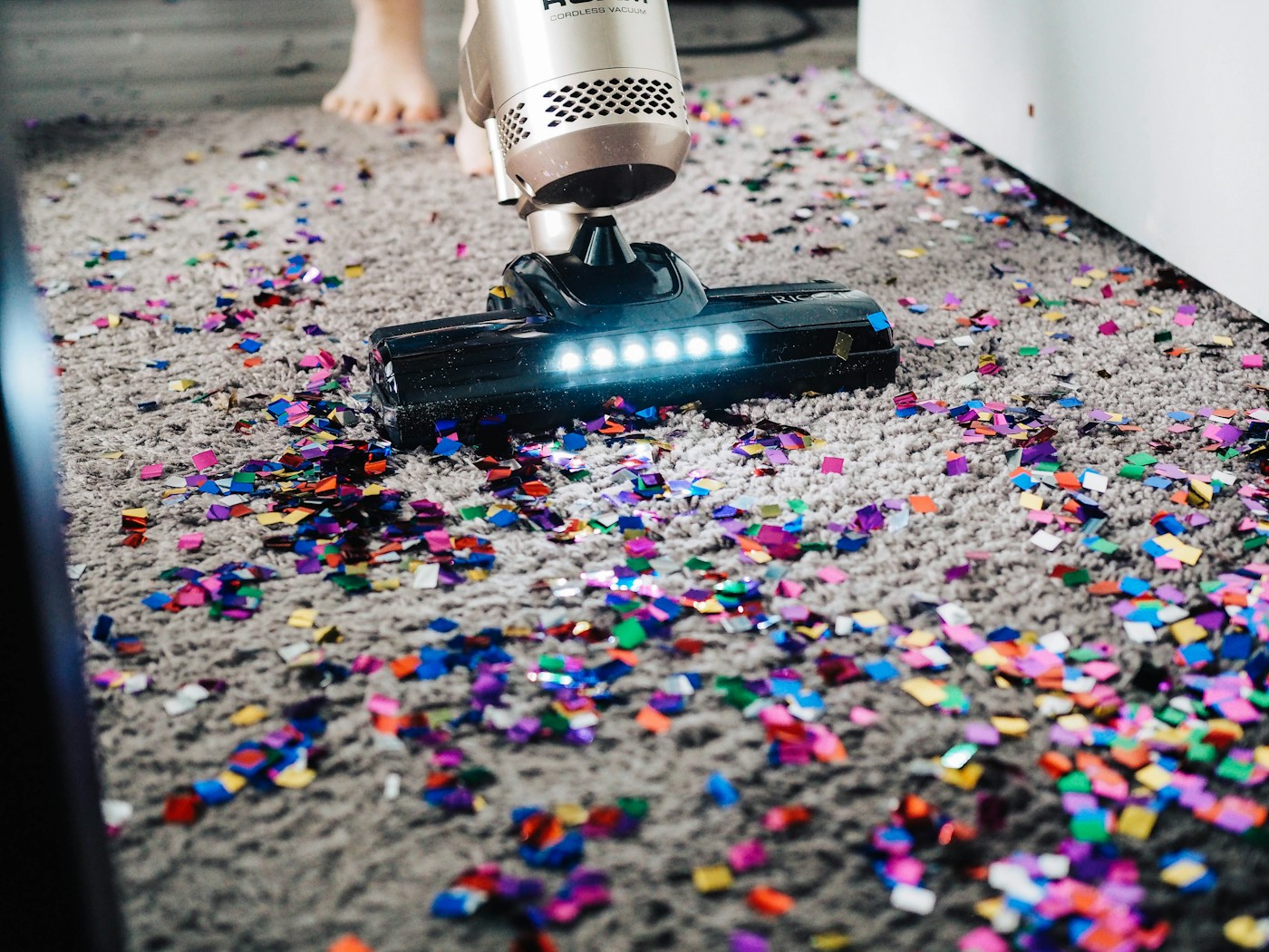 Cleaner wiping a kitchen surface with cleaning supplies nearby